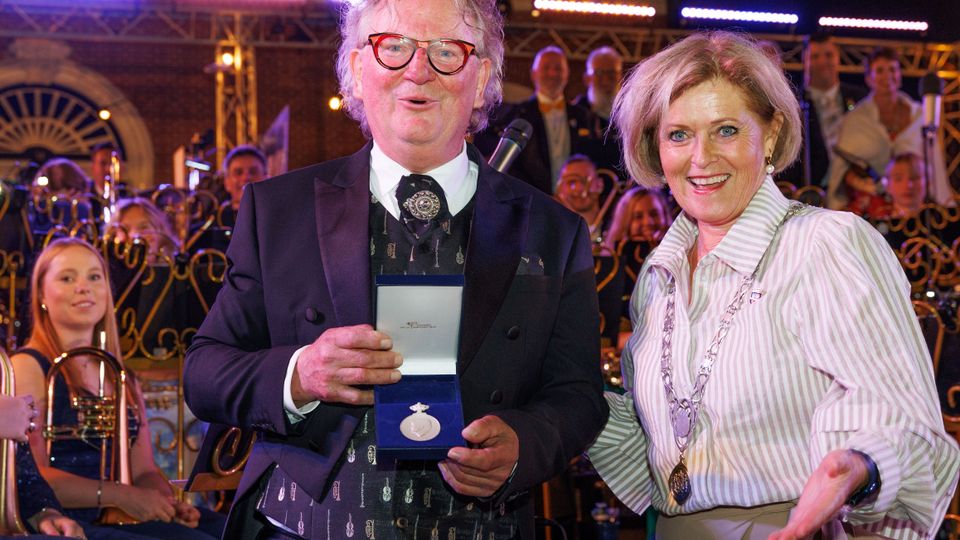Dirigent Walter Siol nam de penning aan van burgemeester Marleen Sijbers. | foto: Gemeente Tholen