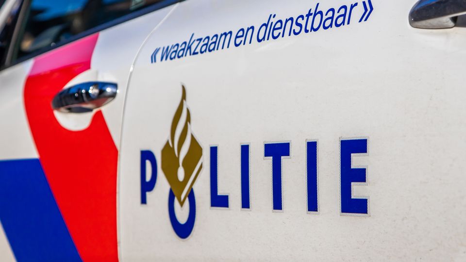 Close-up van de zijkant van een politiewagen met het politielogo en daarboven de tekst 'waakzaam en dienstbaar'
