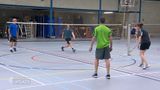 Sporthal met badmintonveld waar vier mensen een dubbelspel spelen
