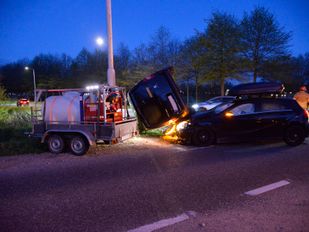 Auto en busje botsen, busje komt op zijkant tegen paal terecht