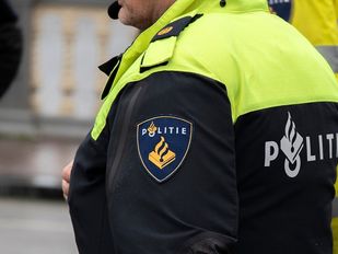 Close-up van de schouder van een agent met politie-embleem op de zijkant van de mouw.