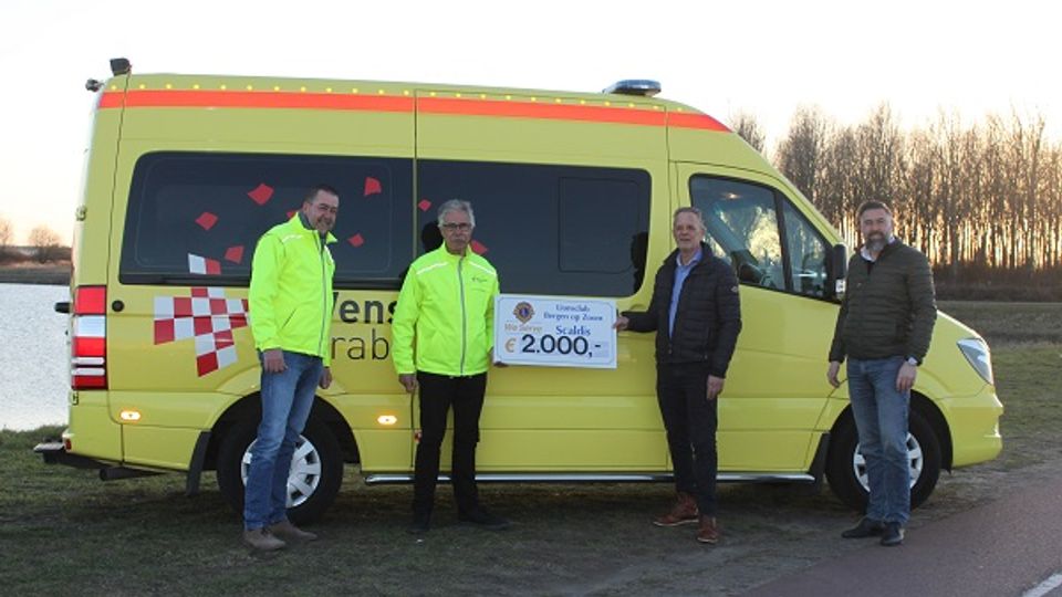 Ambulance met daarvoor twee leden van de Stichting Wensambulance West-Brabant en twee leden van de Lionsclub Bergen op Zoom 