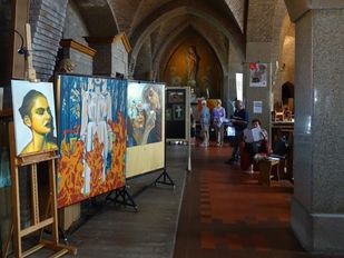 Grote schilderijen staan op schildersezels in het middenschip van een kerk