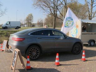 Auto rijdt tussen pionnen door naar verkoopkraam in drive-through