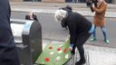Proef met kunstgrasmatten met bloemen bij ondergrondse containers