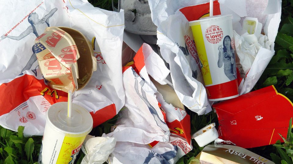 Afvalstapel van gebruikte fastfoodverpakkingen zoals hamburgerdoosjes en milkshakebekers met rietjes