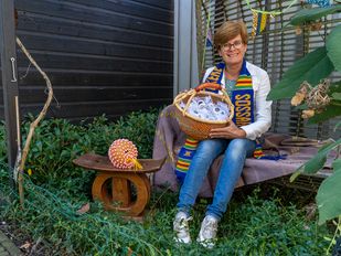 Annemieke de Bruijckere met naast haar een chief-stoel van haar vader, om haar nek een traditionele sjaal en in haar handen een mand vol goodies.