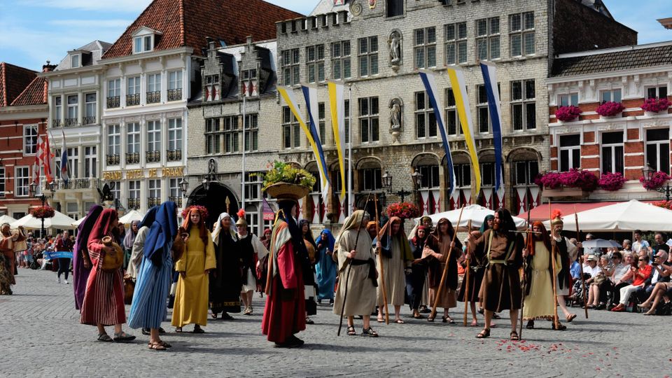 Historisch geklede mensen in stoet over de Grote Markt in Bergen op Zoom voor de Maria Ommegang