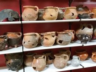 Plankenkast gevuld met archeologische vondsten zoals oude potten