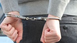 Close-up van handen die op de rug in handboeien zitten