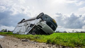 Pakketbezorger eindigt met bestelbus op zijn kop in sloot na aanrijding