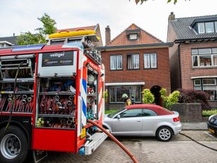 Brandweerwagen voor woningen met hulpverleners in de deuropening van het middelste huis