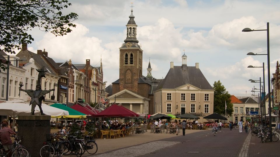 Volle terrassen onder grote parasols op de Markt in Roosendaal met uitzicht op de St Jan en het oude raadhuis