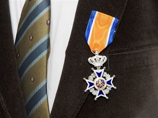 Close-up van koninklijke onderscheiding opgespeld op het rever van een zwart colbert