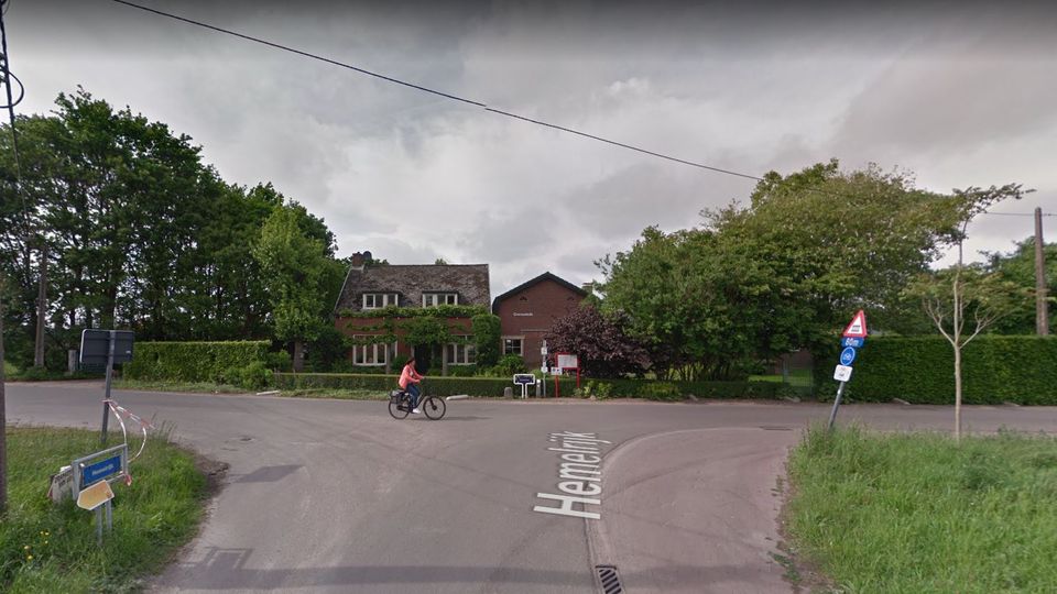 Fietser steekt vanaf links een t-splitsing over met op de achtergrond een woning