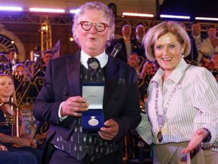Dirigent Walter Siol nam de penning aan van burgemeester Marleen Sijbers. | foto: Gemeente Tholen