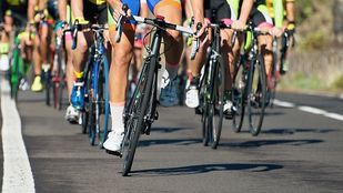 Close-up van wielrennersbenen en racefietsbanden die als groep over asfalt rijden