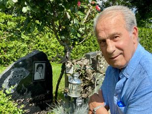 Johan Heeren in blauwe bloes zit op zijn hurken bij het graf van Jack Jersey